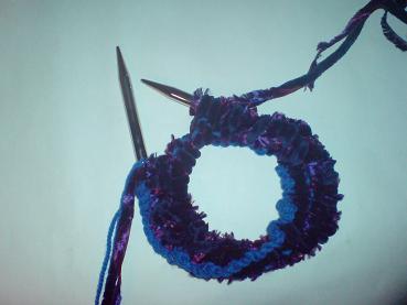 A very narrow piece of knitting, and a circular needle which is coiled round twice